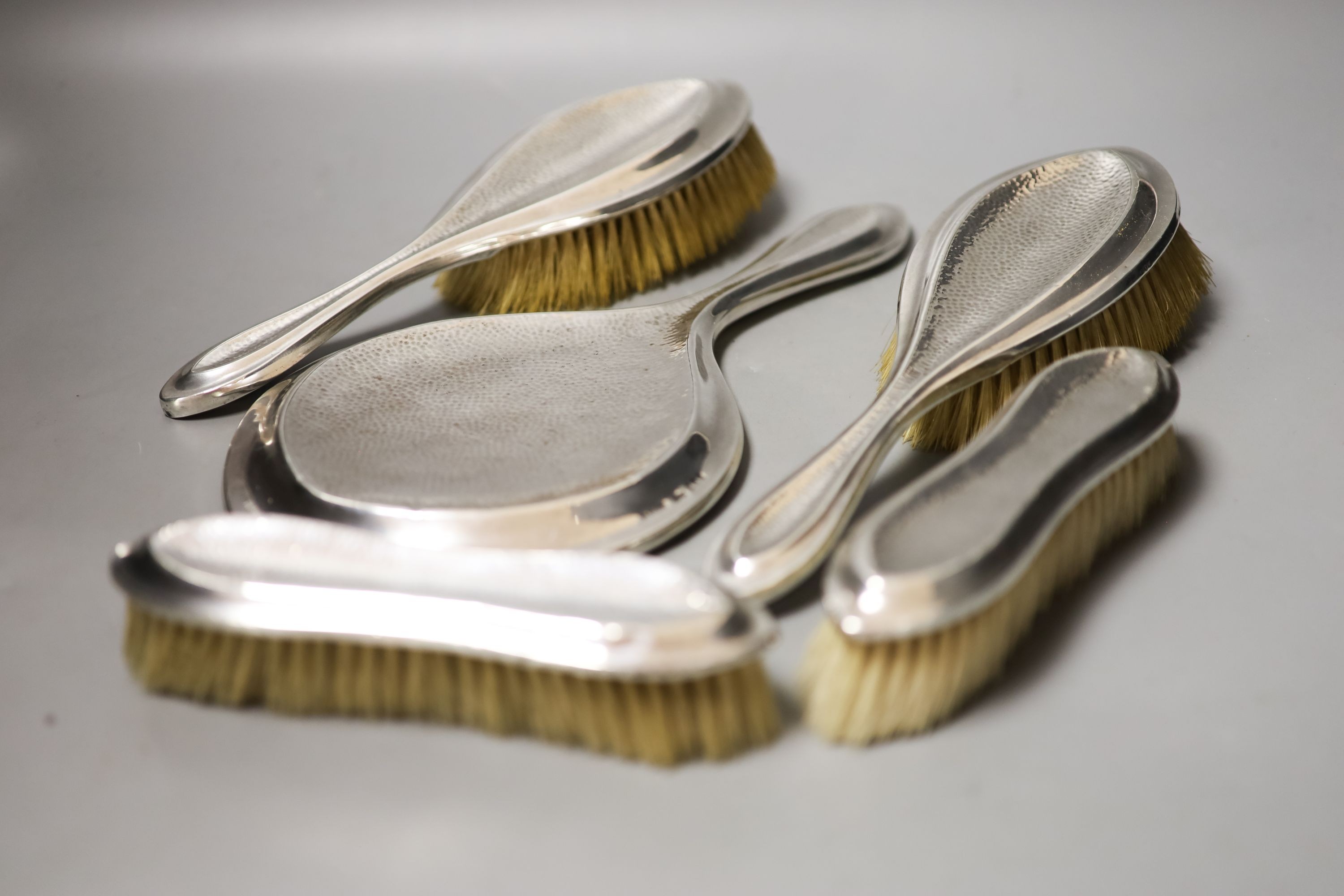 An Edwardian matched part planished silver five piece mirror and brush set, Saunders & Shepherd, Birmingham, 1907/8(4) and Chester, 1908.